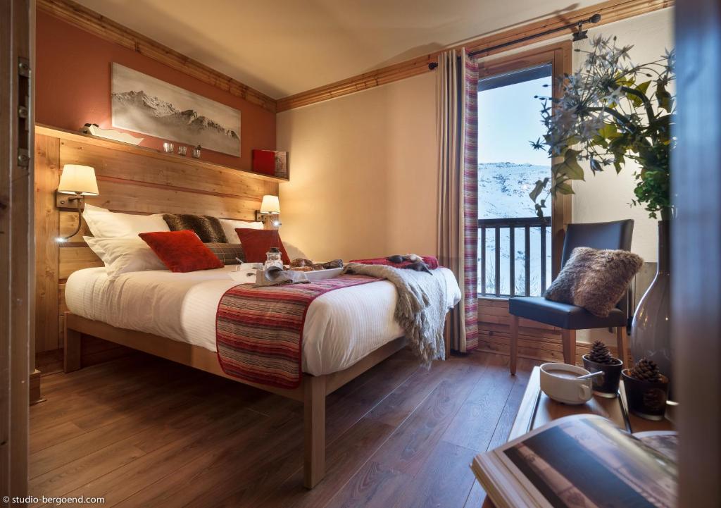 une chambre avec un grand lit et un balcon dans l'établissement Le Hameau de la Sapinière, aux Menuires