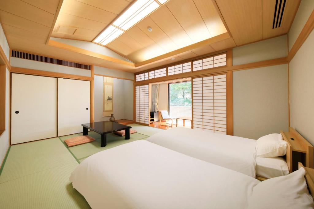 une chambre avec un grand lit blanc et une table dans l'établissement 有馬温泉ラコンテ有馬, à Kobe