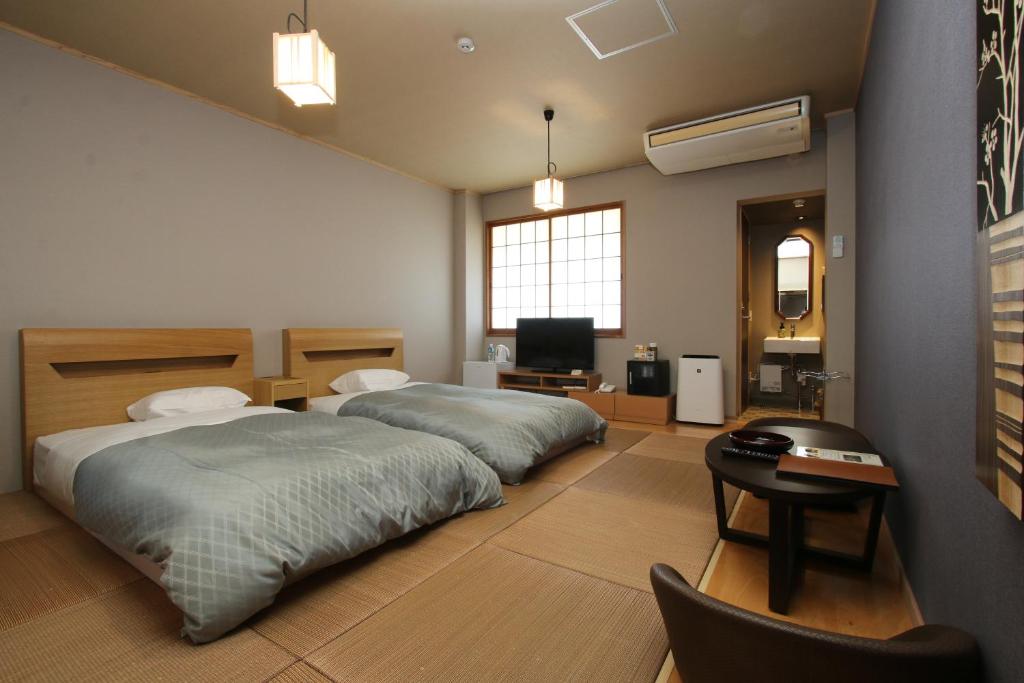 une chambre avec deux lits, un bureau et une télévision dans l'établissement Kafutei, à Yamaga