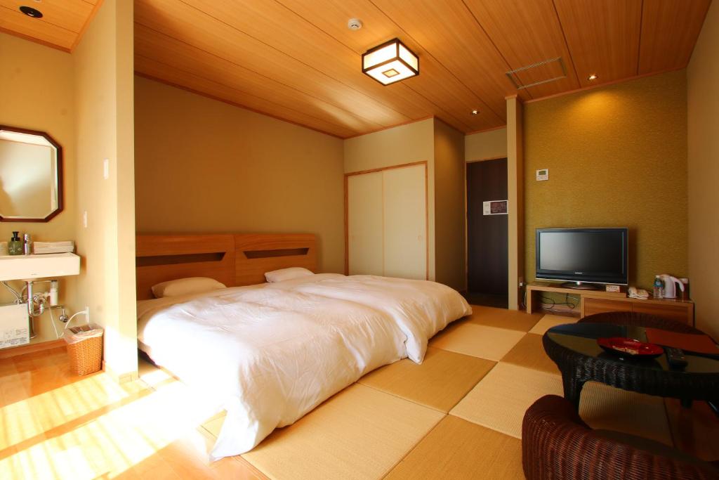 une chambre avec un grand lit et une télévision à écran plat dans l'établissement Kafutei, à Yamaga
