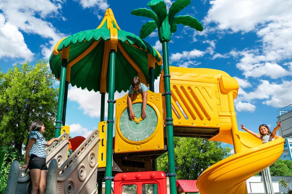 une aire de jeux dans un parc avec des enfants qui jouent dessus dans l'établissement Hotel Eden, à Bibione 13 autres photos
