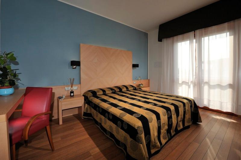 une chambre avec un lit et une chaise rouge dans l'établissement Hotel Eden, à Bibione