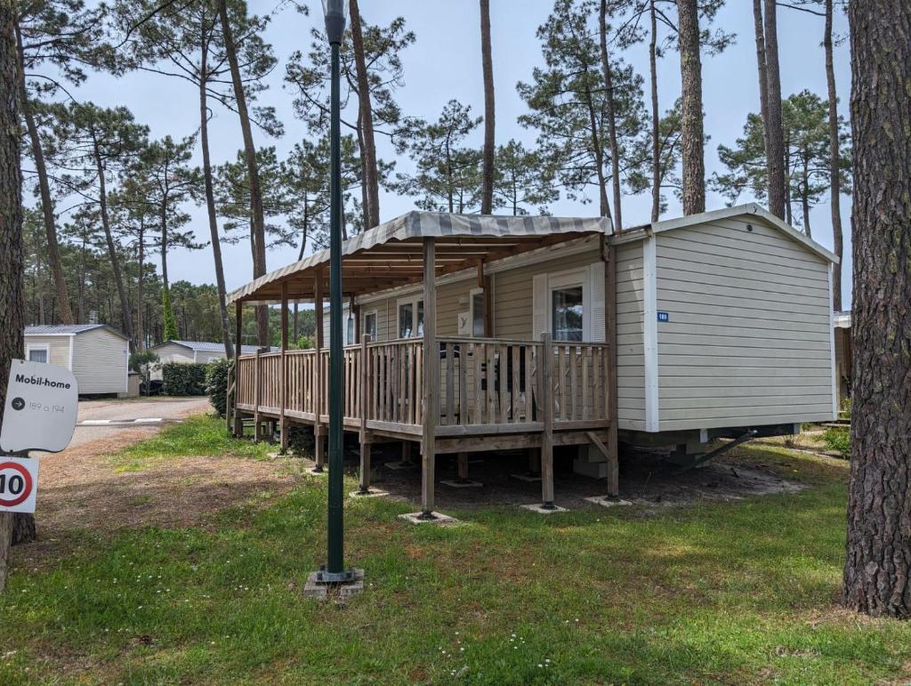 une petite maison avec un porche et une terrasse dans l'établissement Mobil-home Mick et Stefie, à Saint-Julien-en-Born
