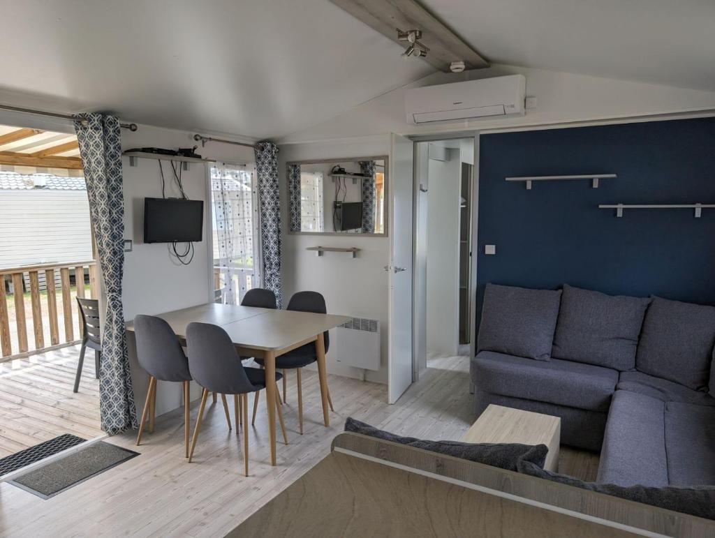 un salon avec une table et un canapé dans l'établissement Mobil-home Mick et Stefie, à Saint-Julien-en-Born