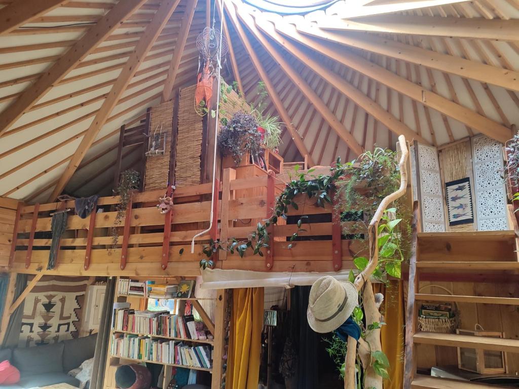 une chambre avec un toit orné de plantes et de livres dans l'établissement Grande yourte, à Boulc
