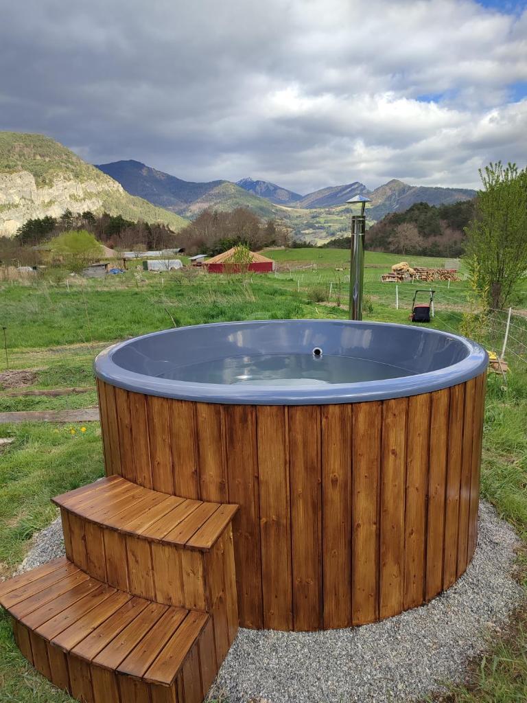 une baignoire en bois entourée d'un banc en bois. dans l'établissement Grande yourte, à Boulc