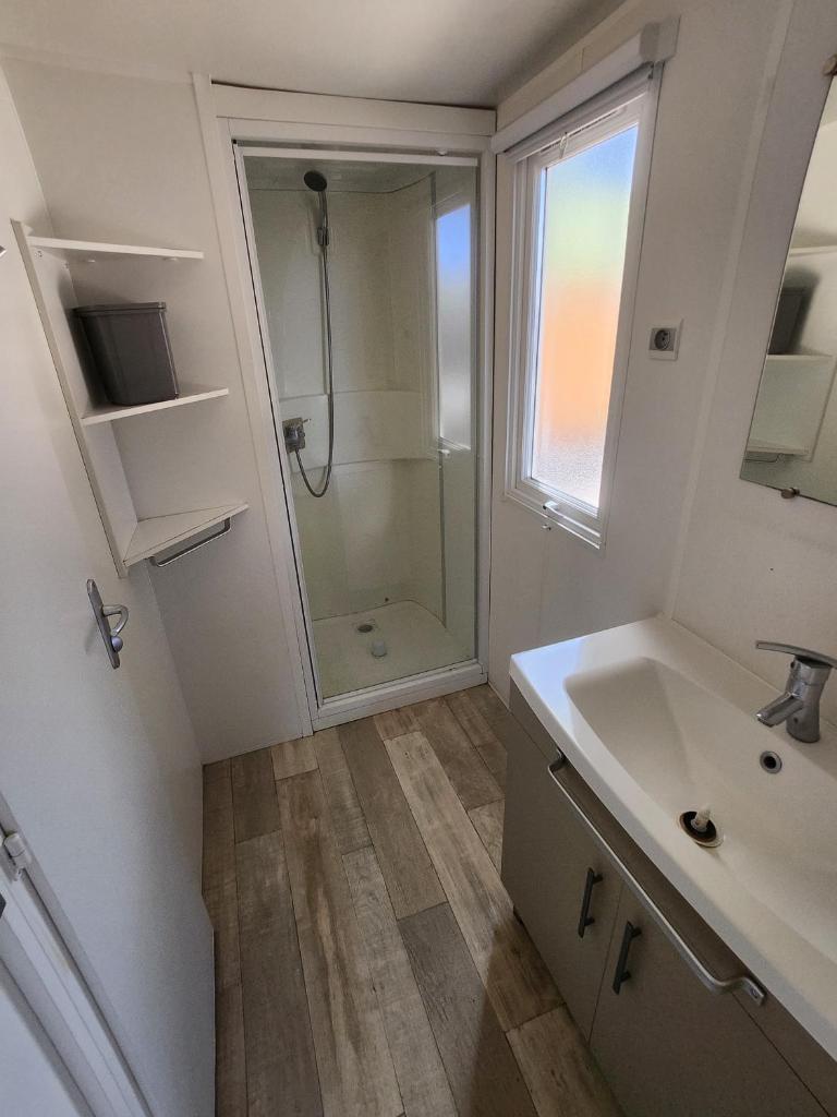 une salle de bain blanche avec une douche et un lavabo dans l'établissement Bungalow confort dans Camping 4 étoiles Marina de Canet Front de mer, à Canet