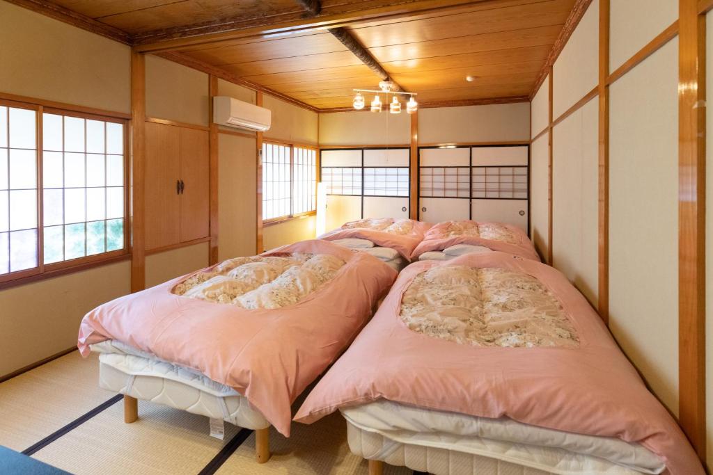 Cette chambre comprend 4 lits avec des draps roses. dans l'établissement Niemonya, à Uozu