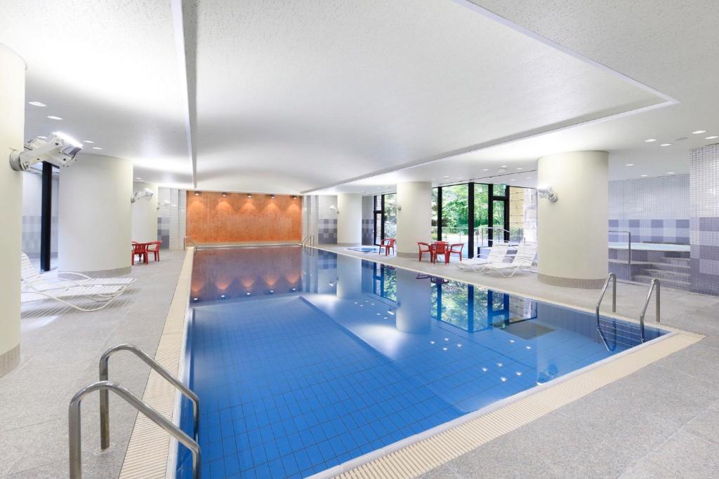 - une grande piscine avec des carreaux bleus dans un bâtiment dans l'établissement 有馬温泉ラコンテ有馬, à Kobe