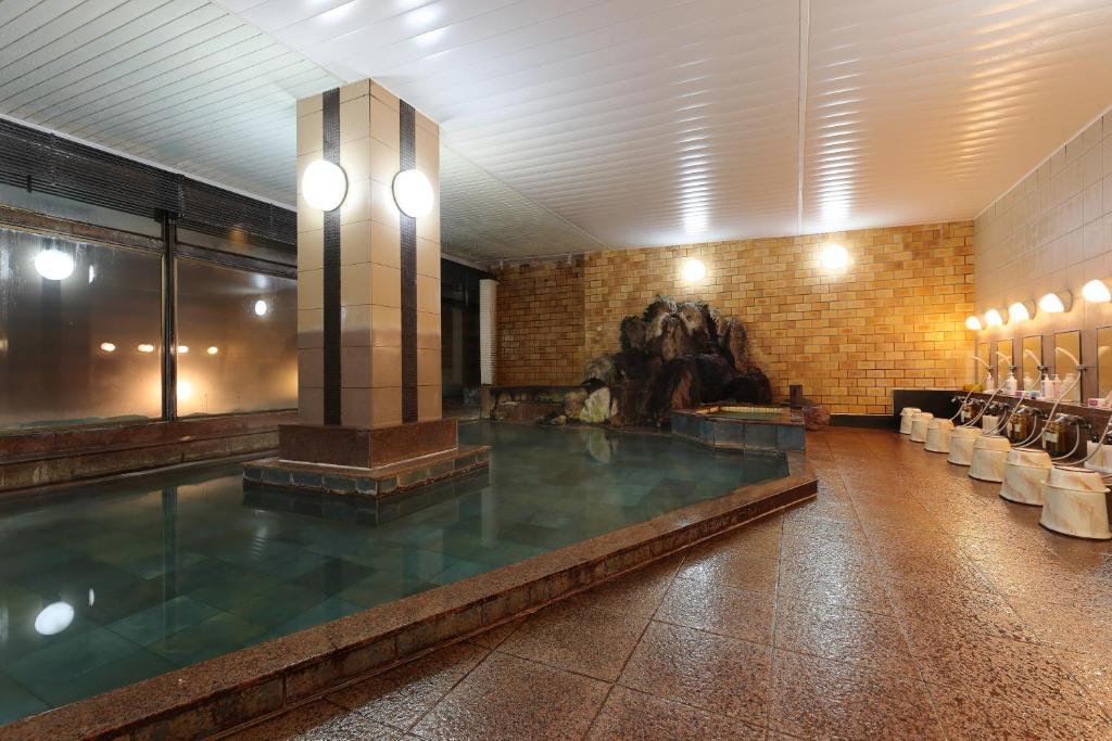 - une grande piscine dans un bâtiment avec une statue dans l'établissement Yorokobinoyado Takamatsu, à Kusatsu