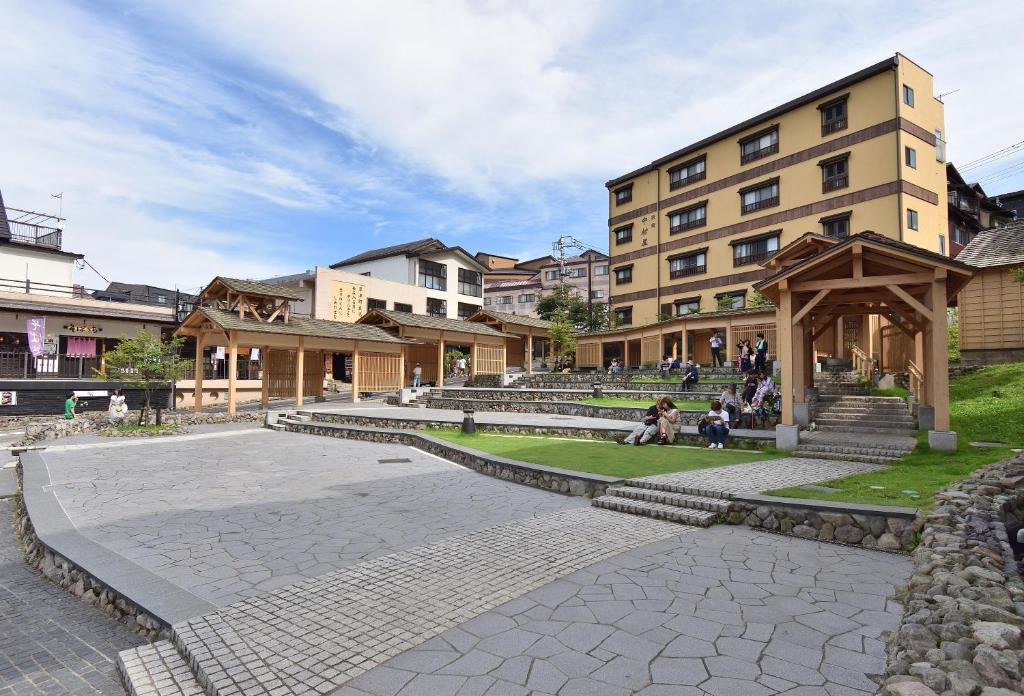 un groupe de personnes assises devant un bâtiment dans l'établissement Yorokobinoyado Takamatsu, à Kusatsu