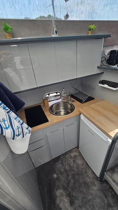 une petite cuisine avec un évier et un comptoir dans l'établissement Nuits insolites sur un bateau 12m en pleine nature, à Bully