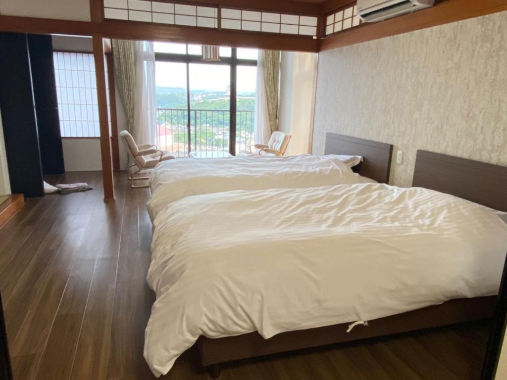 un grand lit blanc dans une chambre avec une fenêtre dans l'établissement Kishotei, à Hirado