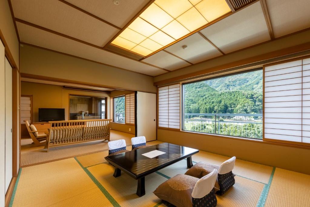 - un salon avec une table, des chaises et une grande fenêtre dans l'établissement Kinugawa Hotel Mikazuki, à Nikkō