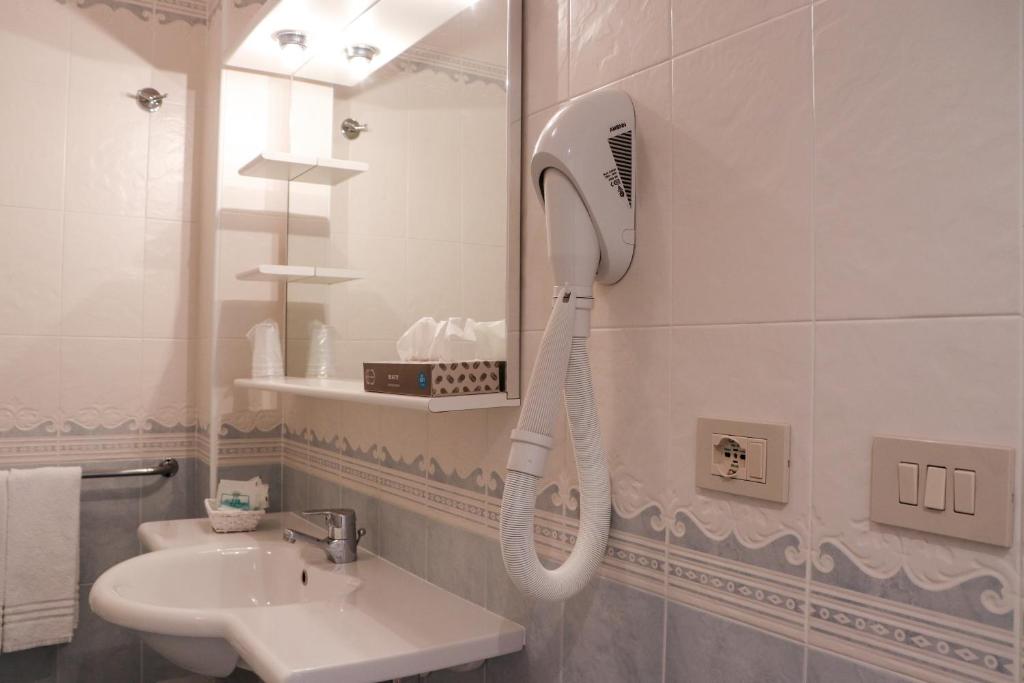 La salle de bains est pourvue d'un sèche-cheveux accroché au mur. dans l'établissement Hotel Principe, à Caorle