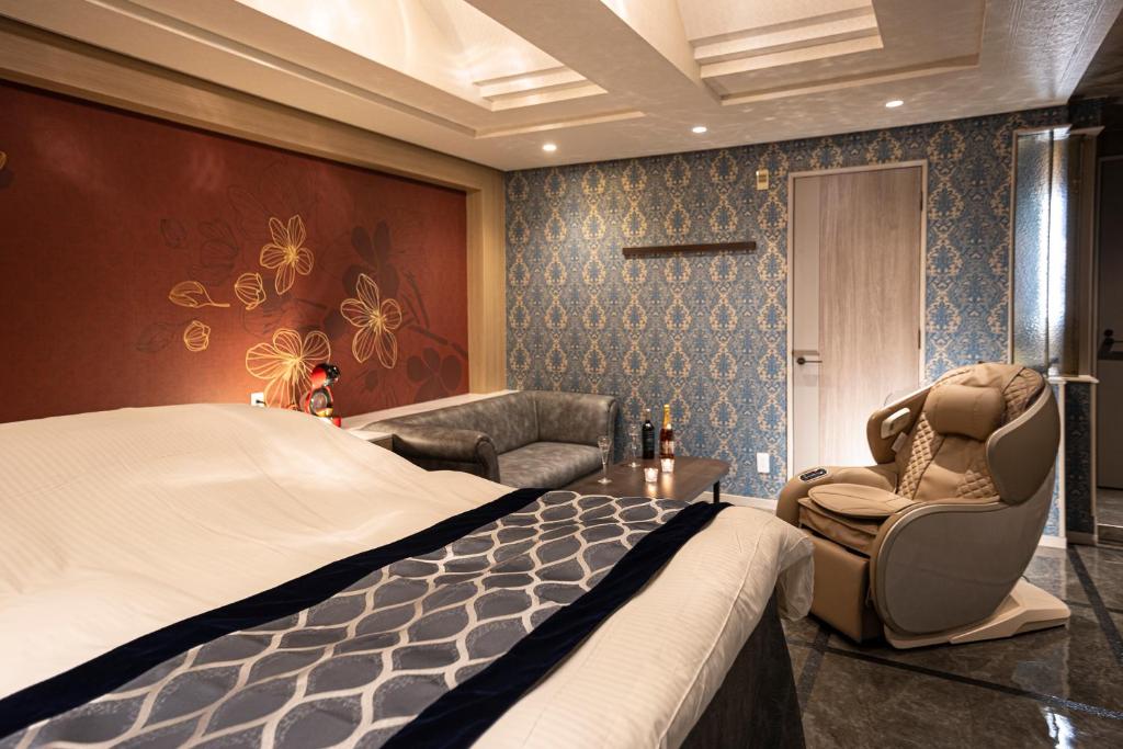 une chambre d'hôtel avec un lit et une chaise dans l'établissement HOTEL X, à Kadoma