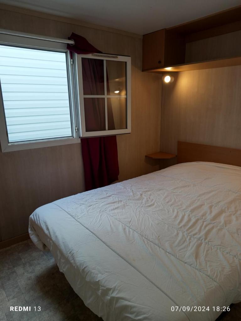 une chambre avec un lit blanc et une fenêtre dans l'établissement vacances familiales dans camping avec piscine, à Fréjus