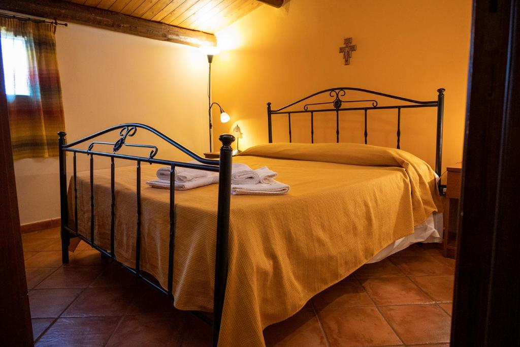 - une chambre dotée d'un lit avec des draps jaunes et une croix dans l'établissement Villa delle Cecilie, à Partinico