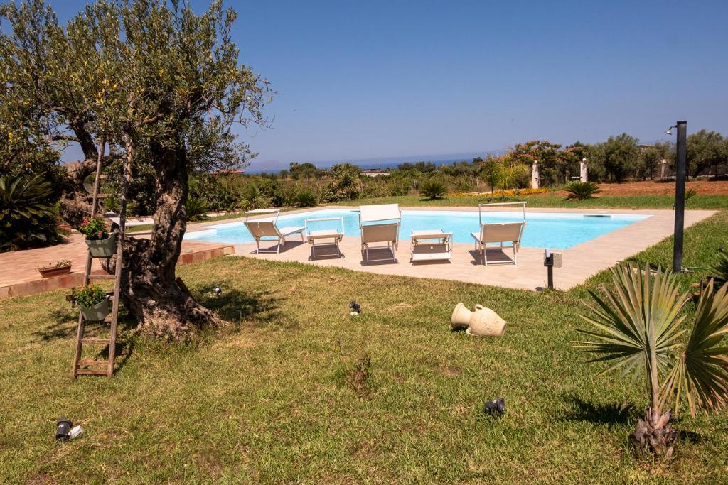 - une piscine avec des chaises et un arbre dans l'herbe dans l'établissement Villa delle Cecilie, à Partinico