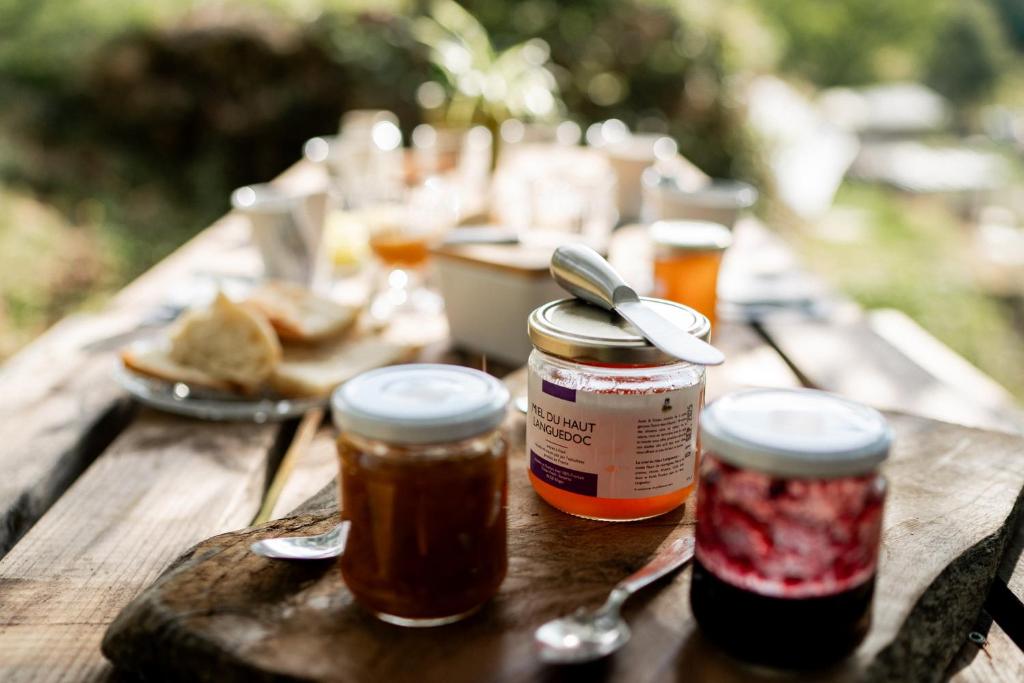 une table en bois avec des bocaux de confiture et une assiette de nourriture dans l'établissement Altitude Ecolodge Yourte, à Ilonse