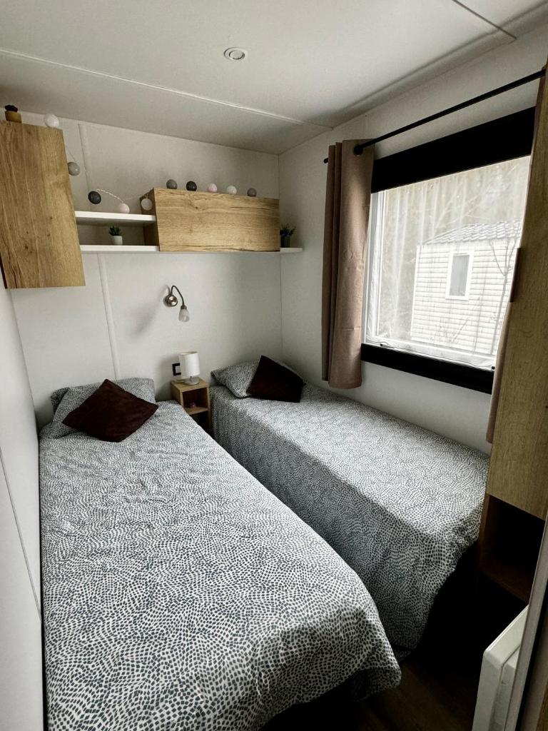 deux lits dans une petite pièce avec une fenêtre dans l'établissement Mobile-home 3 chambres chaleureux et calme, à Seillac