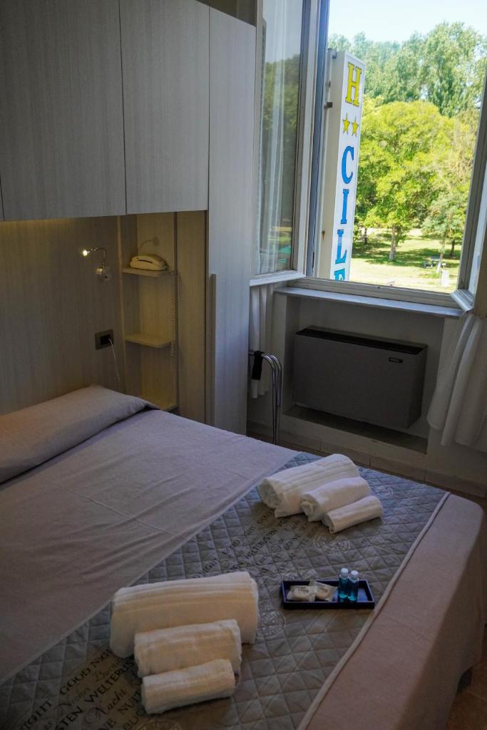 - une chambre avec un lit, des serviettes et une fenêtre dans l'établissement Hotel Cilene, à Viareggio