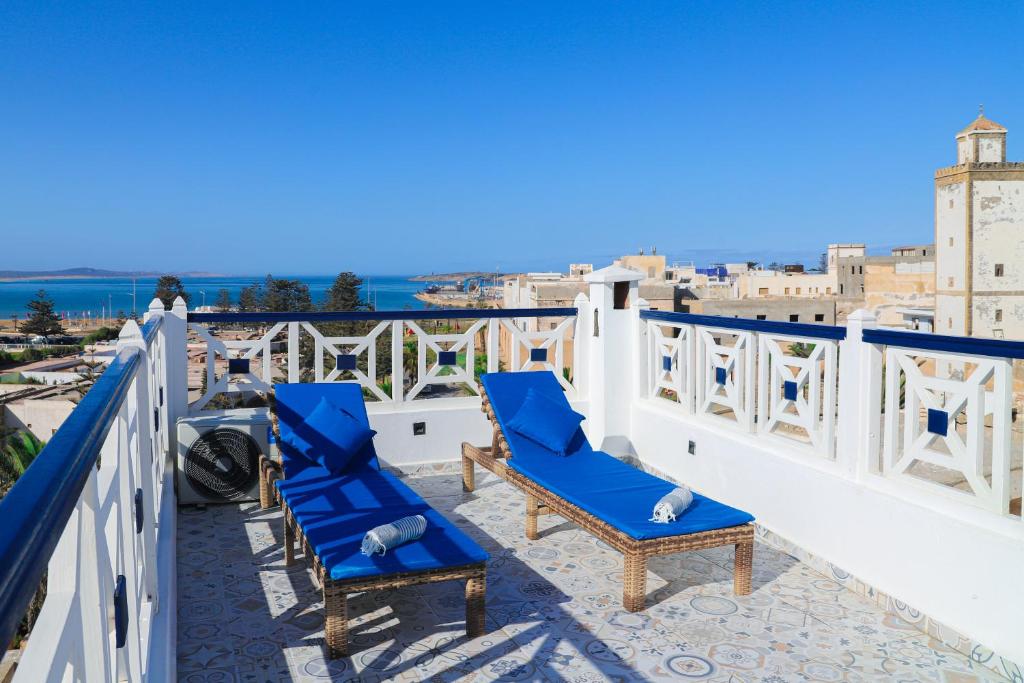 d'un balcon avec des chaises bleues et une vue sur la ville. dans l'établissement Riad YAHIA ZAMANE, à Essaouira