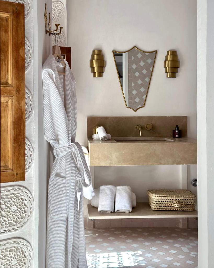 une salle de bain avec un lavabo et une étagère avec des serviettes dans l'établissement Riad Jalma, à Marrakech