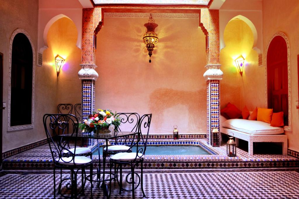 une chambre avec une table et des chaises à côté d'une piscine dans l'établissement Riad Charik, à Marrakech
