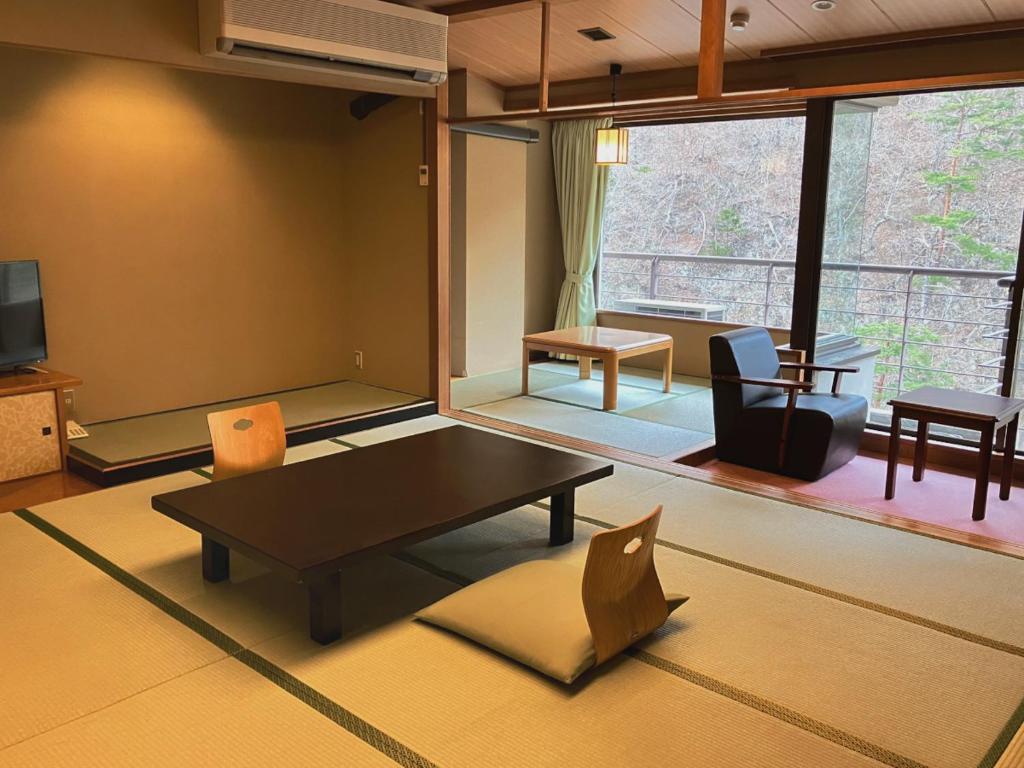 un salon avec une table, des chaises et une télévision dans l'établissement Hotel Yunishigawa, à Nikkō