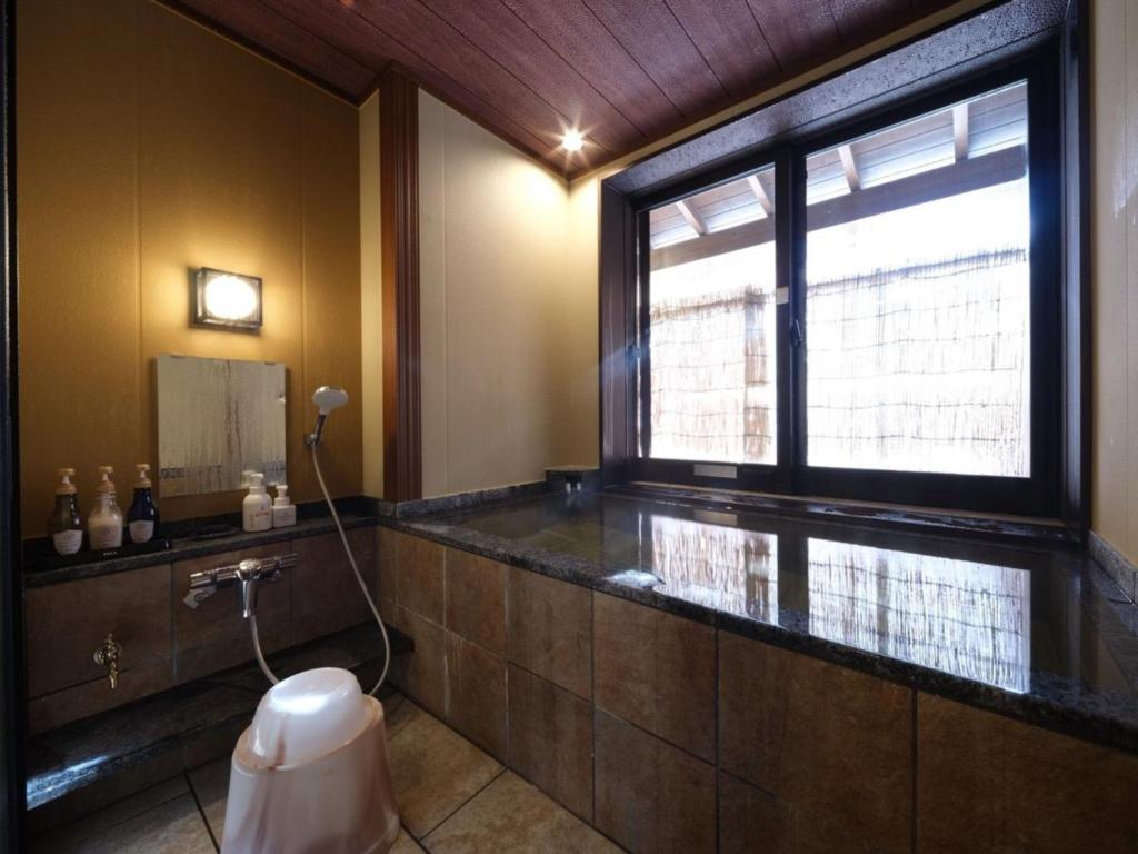 La salle de bains est pourvue d'une fenêtre et de toilettes. dans l'établissement Nakaya Ryokan, à Minakami