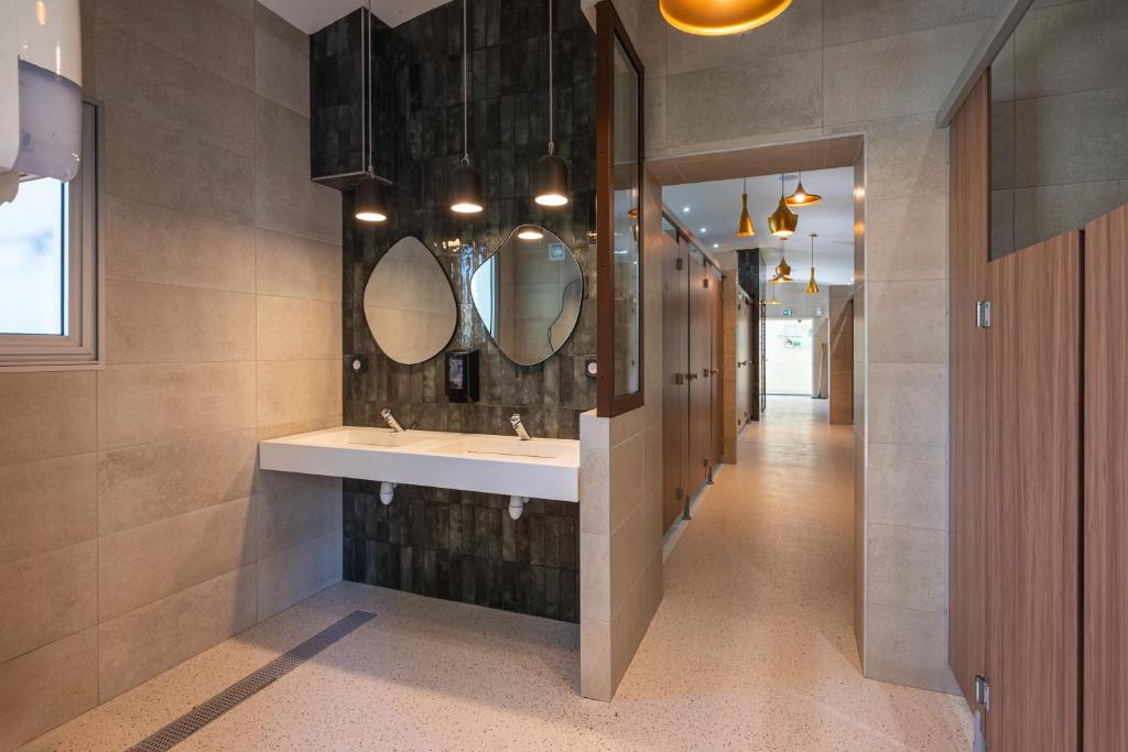 une salle de bain avec un lavabo et des miroirs au mur dans l'établissement Camping RCN Domaine de la Noguière, au Muy 37 autres photos