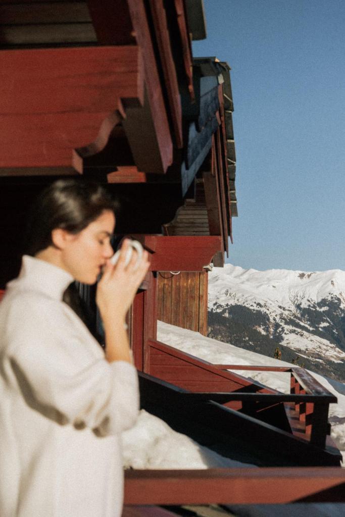un homme assis sur un balcon parlant sur un téléphone portable dans l'établissement Hotel Carlina, à Courchevel