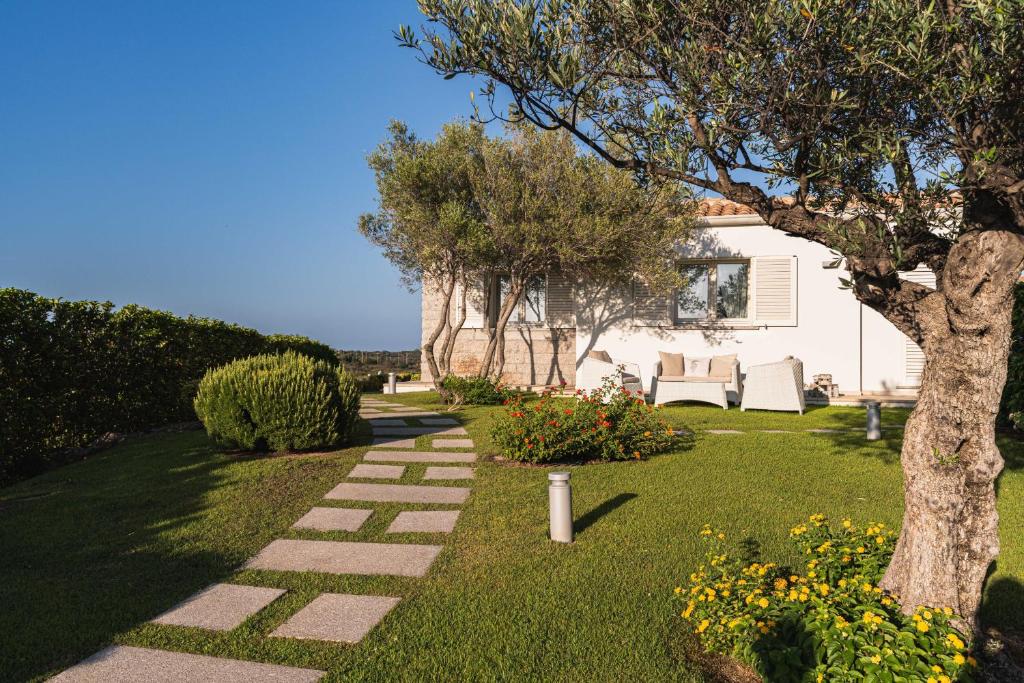 un jardin avec un arbre et un chemin en pierre dans l'établissement Villa Blue Sphere with Pool by Wonderful Italy, à Olbia