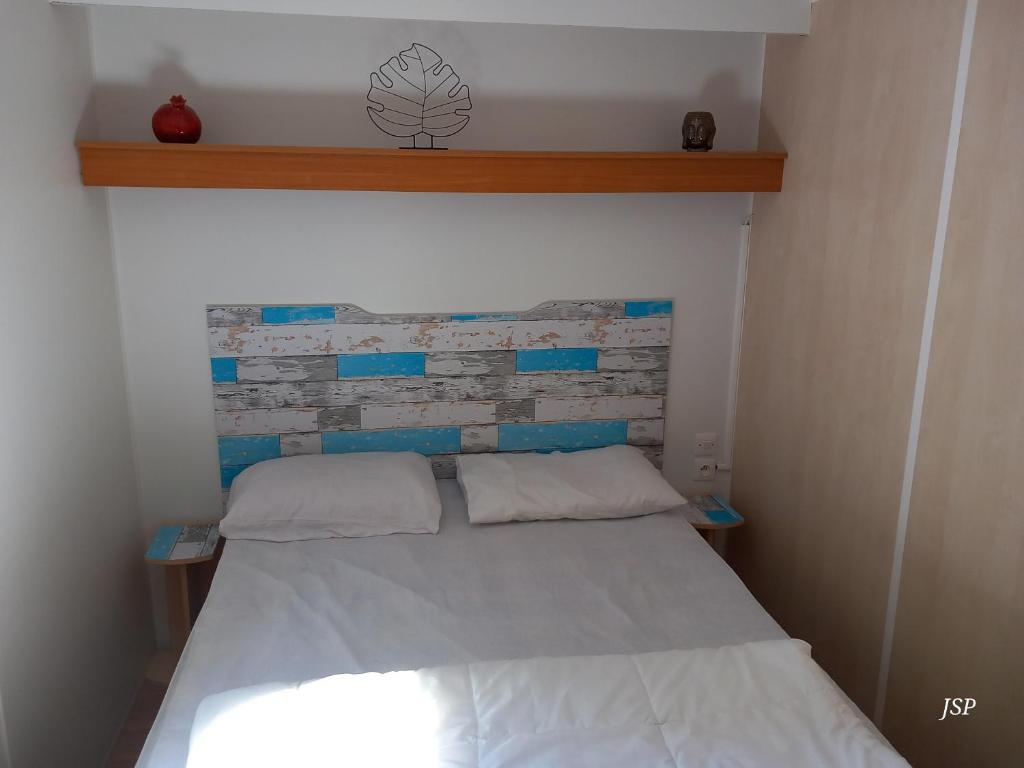 - une petite chambre avec un lit blanc et un mur en briques dans l'établissement Mobilhome Les volets bleus, à Vaudreuille 12 autres photos