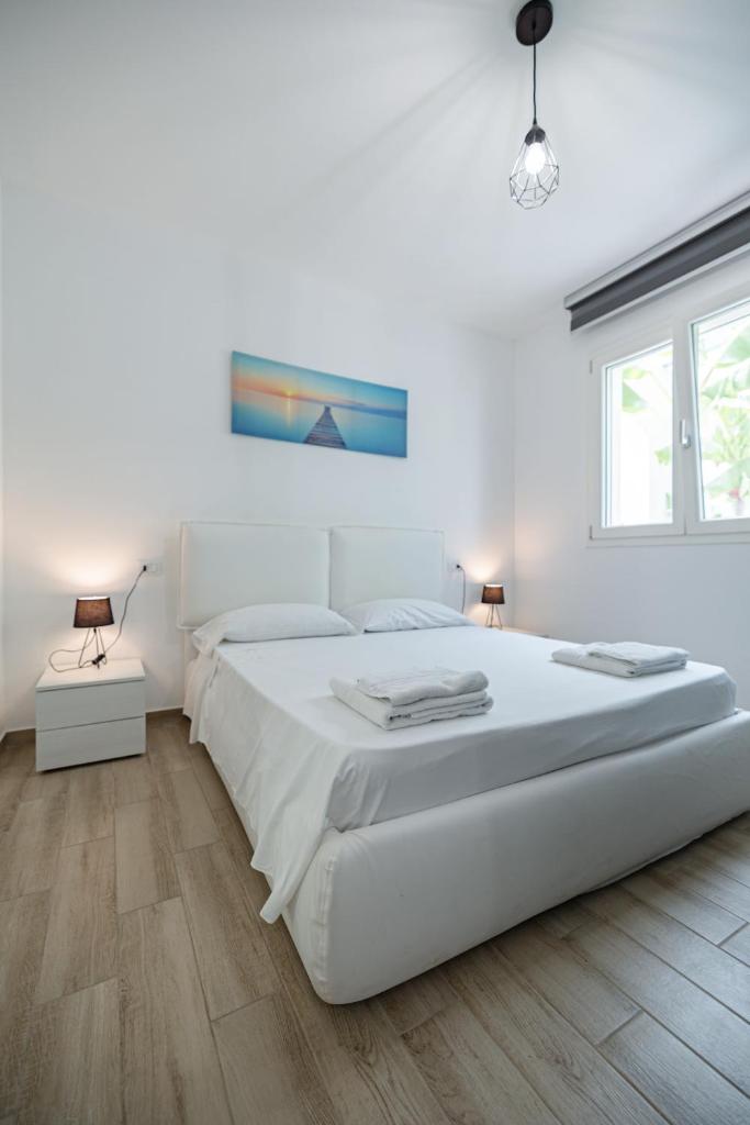 - une chambre blanche avec un grand lit blanc et du parquet dans l'établissement Villa Portofino, à Campofelice di Roccella