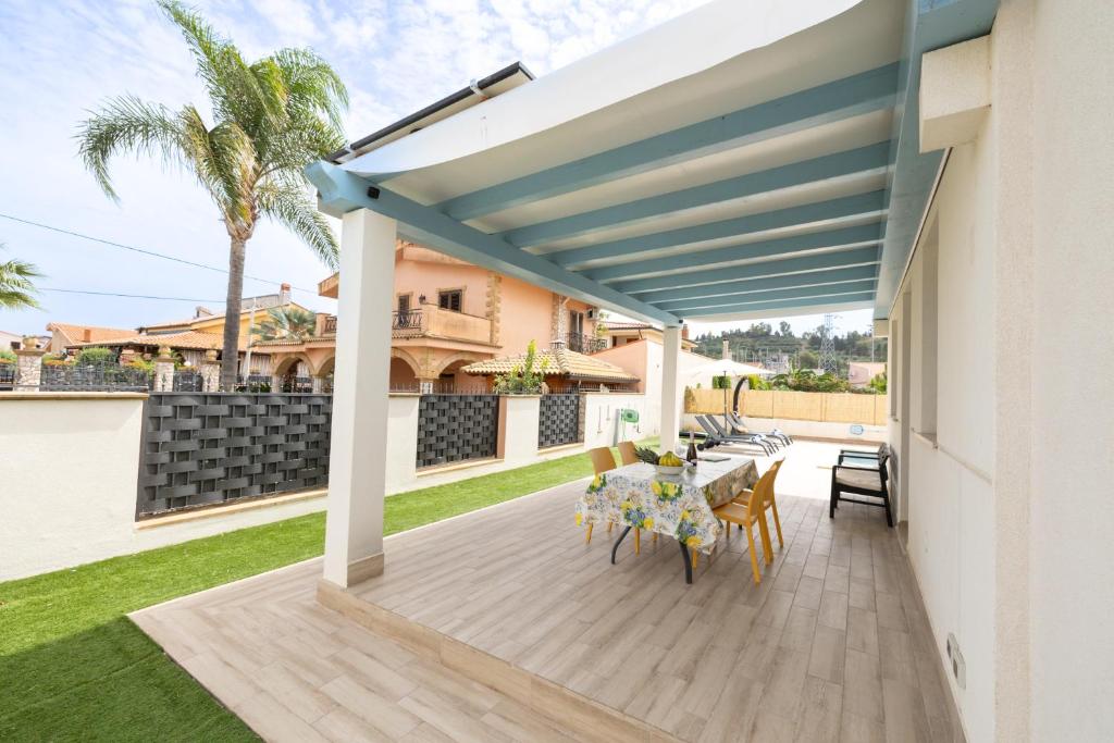 une terrasse avec un auvent bleu, une table et des chaises dans l'établissement Villa Portofino, à Campofelice di Roccella