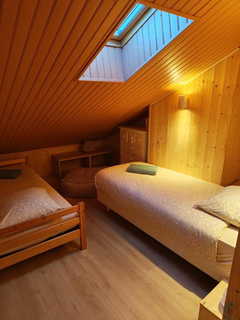 une chambre mansardée avec deux lits et une lucarne dans l'établissement Bel appartement type chalet avec balnéo et jardin, à Gréolières