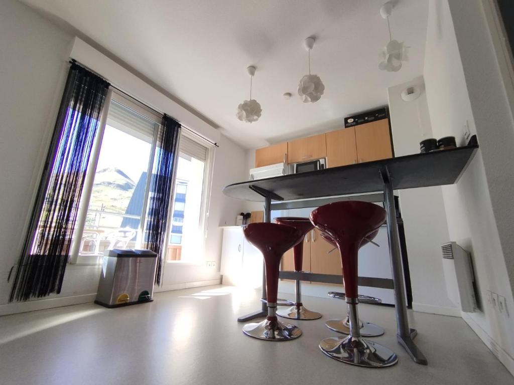 une cuisine avec deux tabourets de bar rouge sous un comptoir dans l'établissement Apartamento AUÑAMENDI Pyrénées, à La Pierre Saint Martin