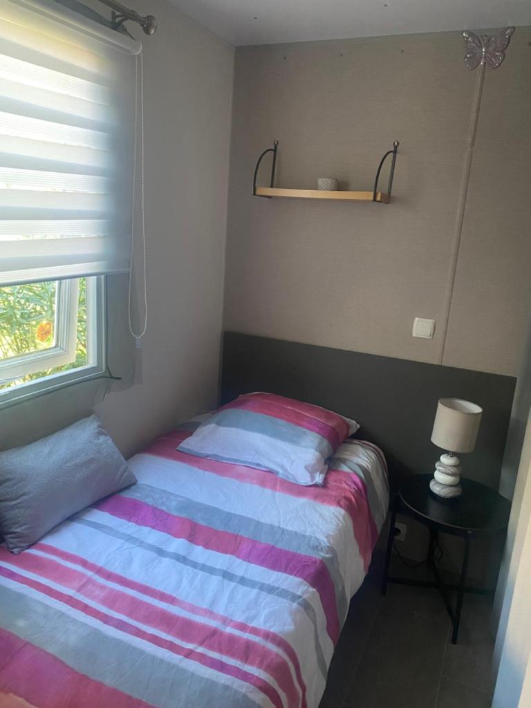 une petite chambre avec un lit et une fenêtre dans l'établissement Oasis de détente, à Fréjus