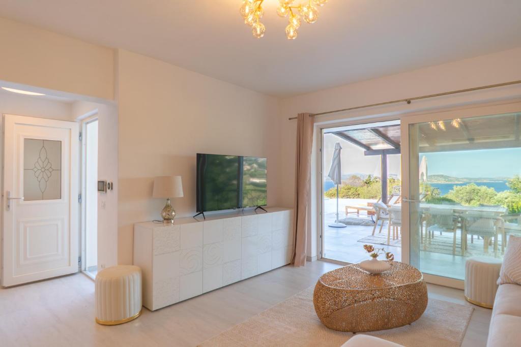 un salon avec une télévision et une table dans l'établissement Villa Gerani Luxus mit Meerblick, à Porto Rafael