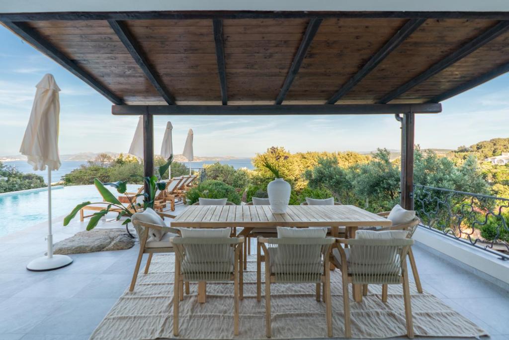 une salle à manger extérieure avec une table et des chaises en bois dans l'établissement Villa Gerani Luxus mit Meerblick, à Porto Rafael