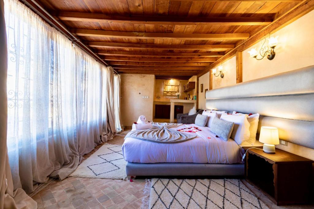 une chambre avec un grand lit et une grande fenêtre dans l'établissement Dar Attajalli, à Fès