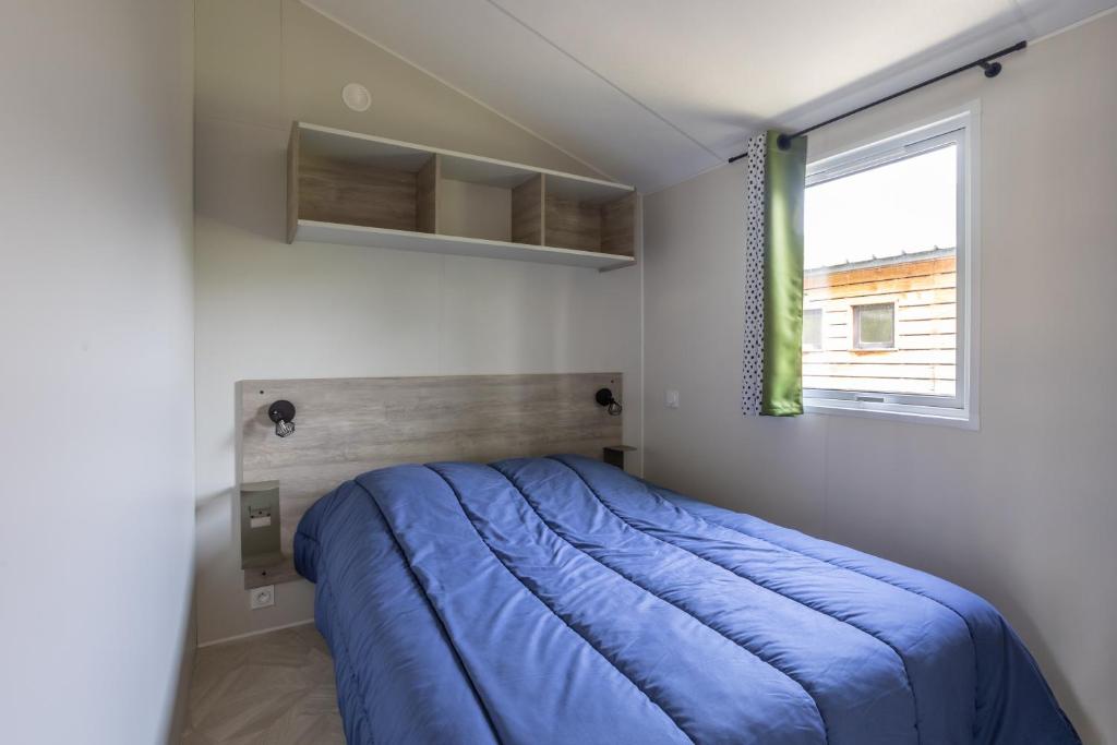 une chambre avec un lit bleu et une fenêtre dans l'établissement Camping le Petit Liou Sites & Paysages, à Baratier 37 autres photos