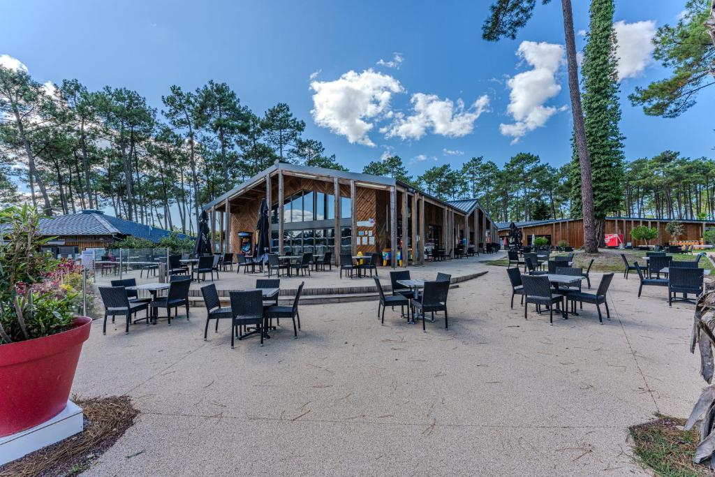 un patio avec des chaises et des tables et un bâtiment dans l'établissement les dunes de contis, à Saint-Julien-en-Born