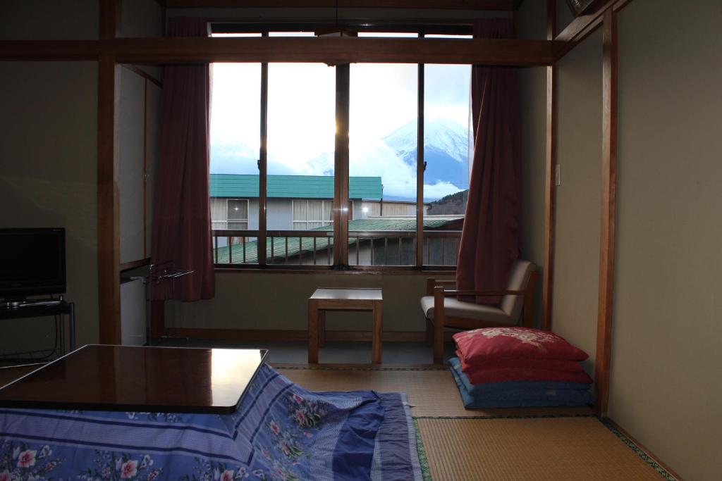 - une chambre avec une grande fenêtre offrant une vue sur la montagne dans l'établissement Sugakuso, à Yamanakako