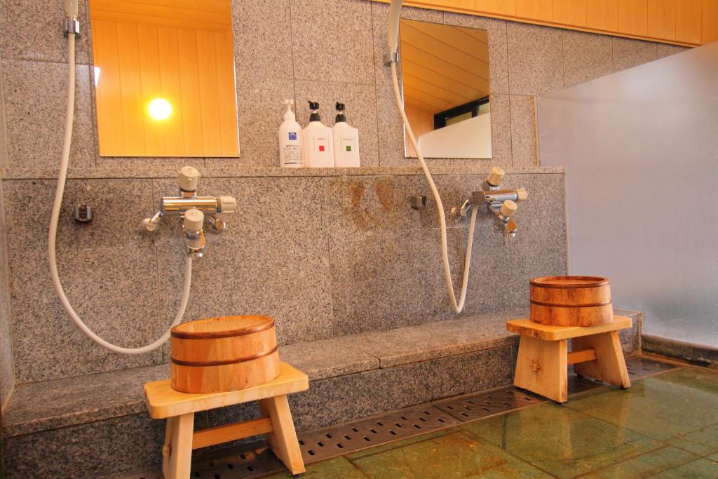 La salle de bains est pourvue d'une douche avec deux tabourets en bois. dans l'établissement Hotel Asafuji, à Fujikawaguchiko