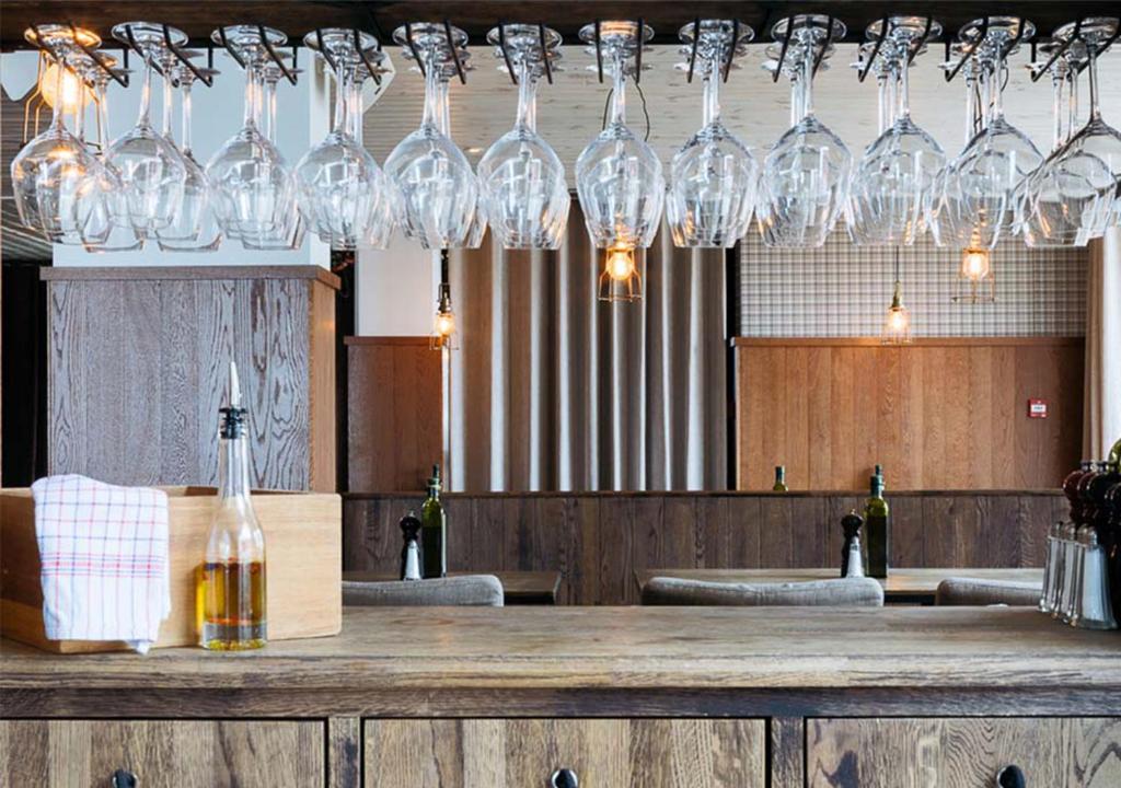 une bande de verres à vin suspendus au-dessus d'un bar dans l'établissement Langley Hôtel Tango, à Val Thorens