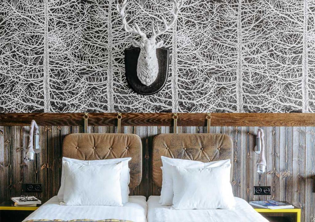 - une chambre avec 2 lits et un mur orné d'une fresque murale représentant des cerfs dans l'établissement Langley Hôtel Tango, à Val Thorens
