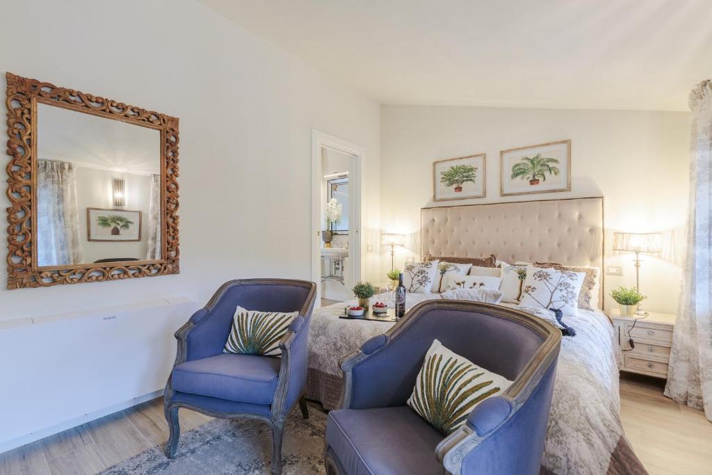 - une chambre avec un lit, deux chaises et un miroir dans l'établissement VILLA ASTI: Where Luxury Meets Limitless View, à Capannori